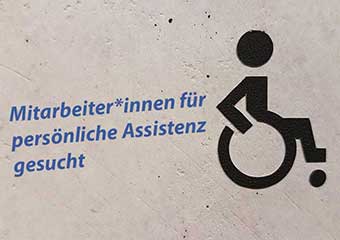 Ambulante-Dienste-eV-Muenster Auf einem Wandschild mit Rollstuhlsymbol steht „Mitarbeiter*innen für persönliche Assistenz gesucht“.